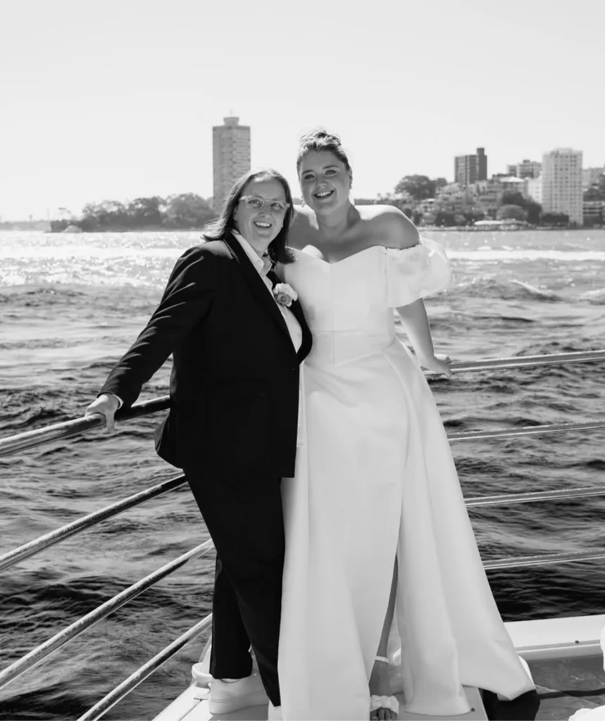 Dot and Katie on their wedding day. Dot in a stunning white dress and Katie in a chic suit on a boat on Sydney's harbour.
