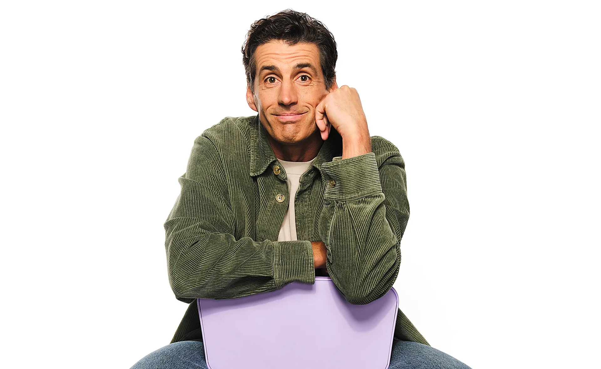 Andy Lee, in a green shirt, sits backwards on a chari