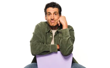 Andy Lee, in a green shirt, sits backwards on a chari