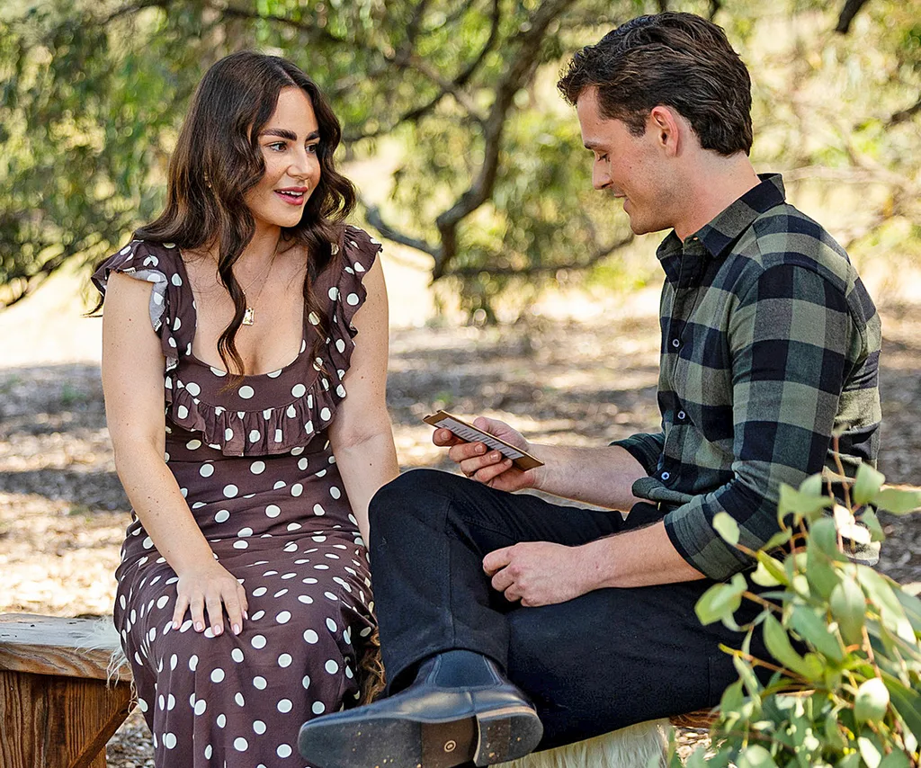 Alex, in a checked shirt, chats to Delia, in a spotted dress, sitting outside