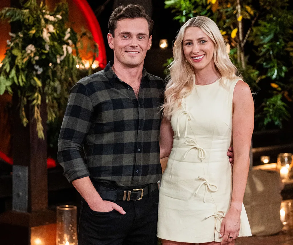 Alex, in a checked shirt, stands next to Eddy, in a white dress