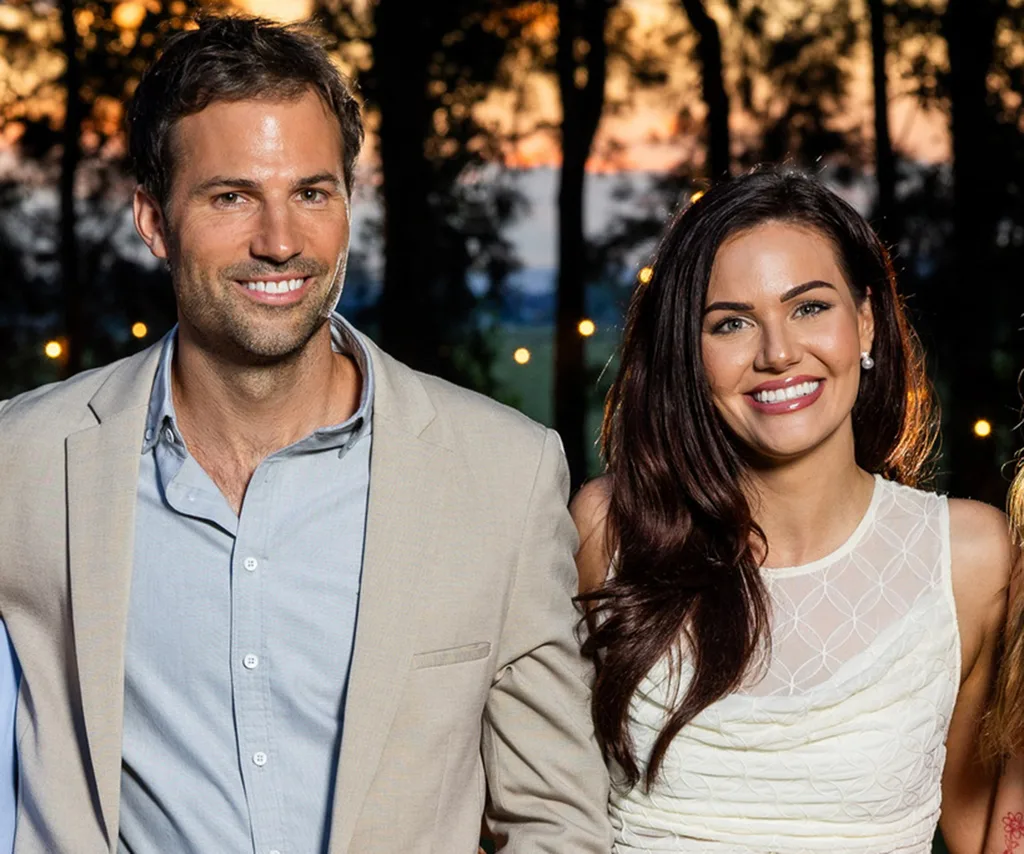 Jarrad and Cara stand next to each other with a sunset behind them