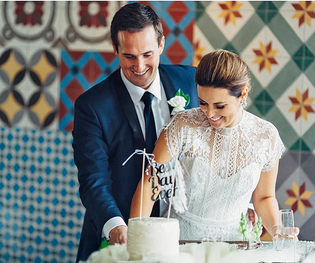James, in a suit, and his bride Lisa, in a white dress, cut their wedding cake