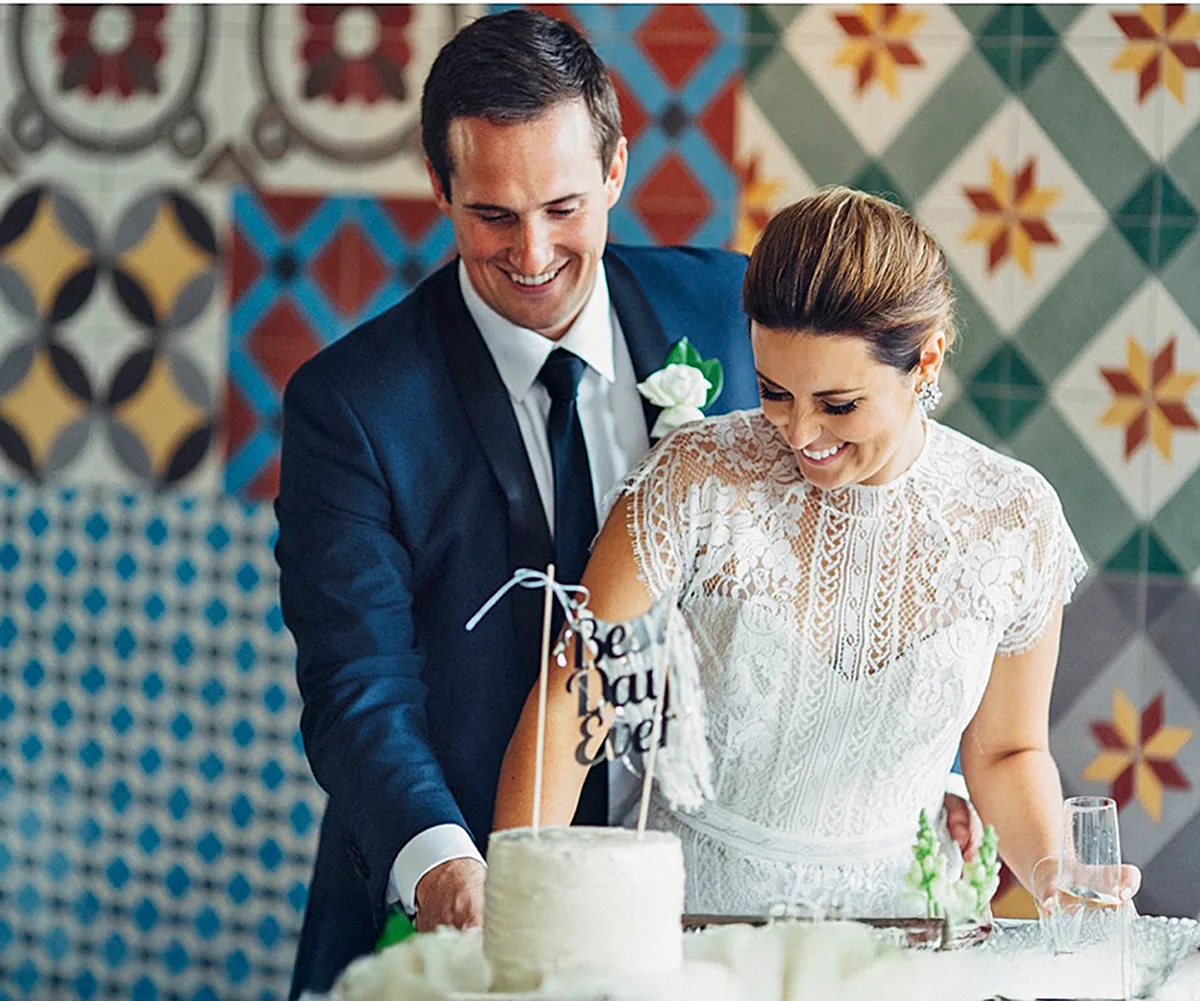 James, in a suit, and his bride Lisa, in a white dress, cut their wedding cake