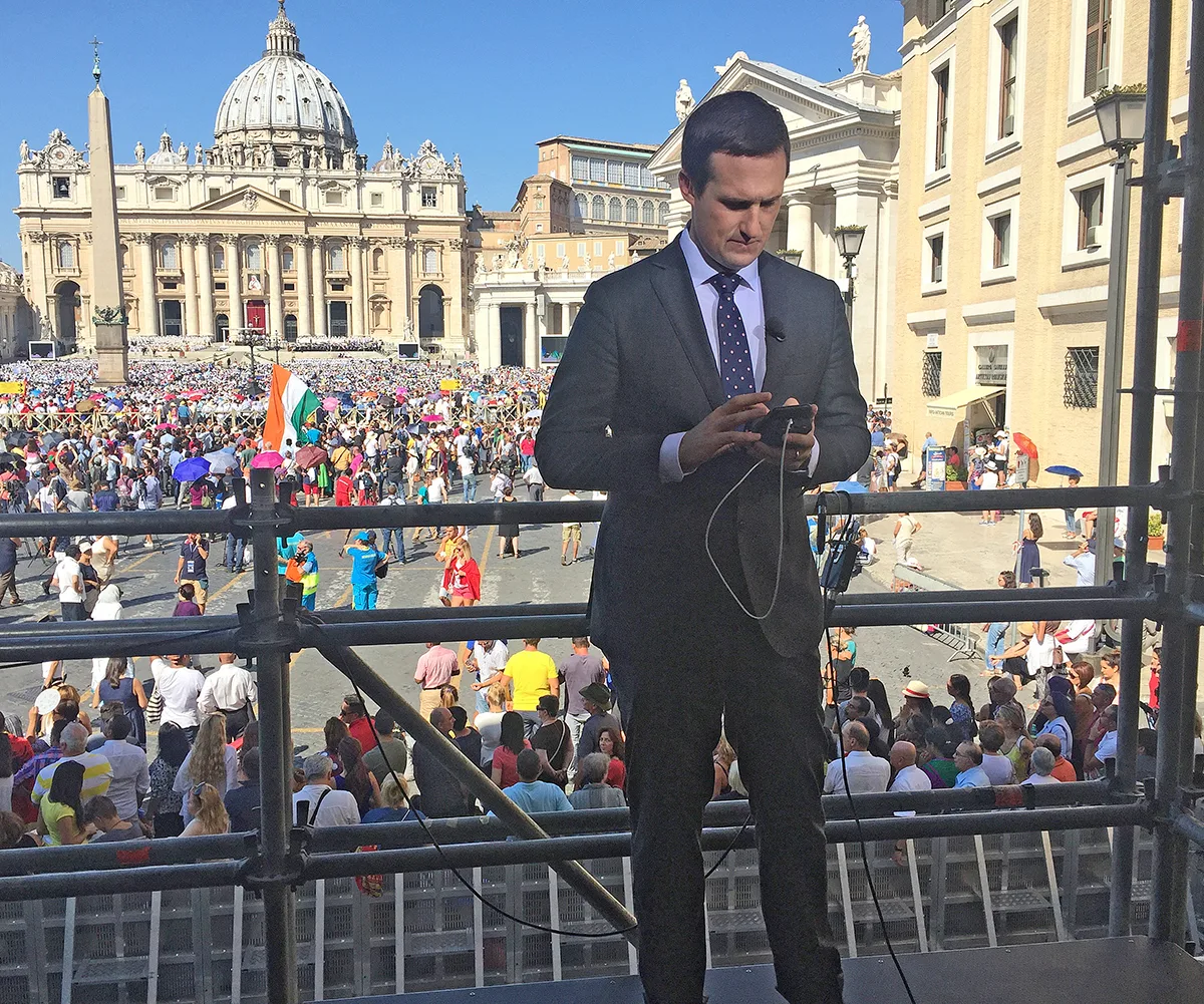 James, looking down, with the buildings of the Vatican behind him