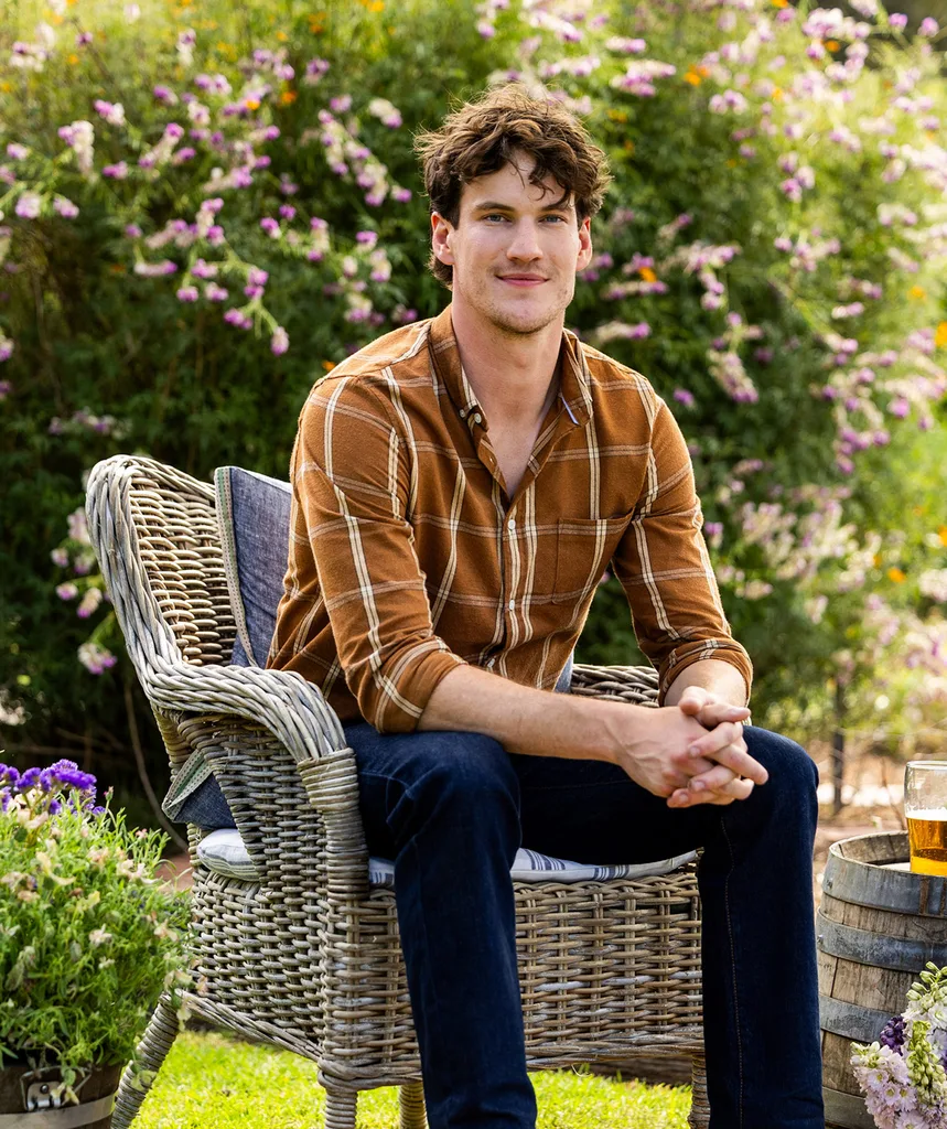 Farmer Zac, in a brown shirt, sits on a chair