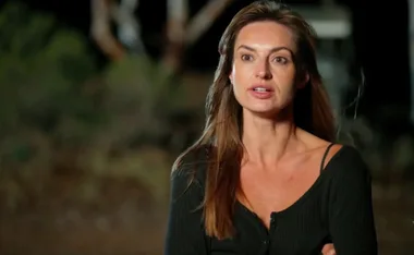 Christina wearing a black top, stands outside at night