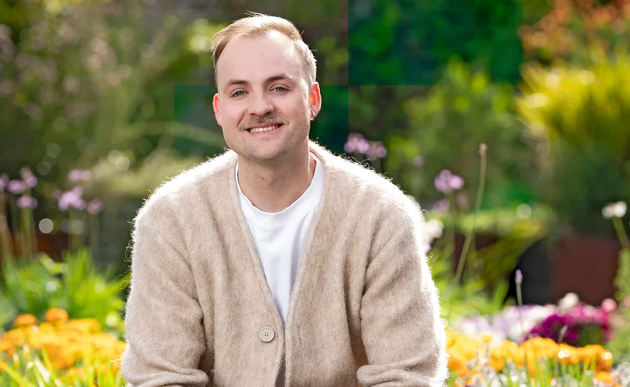 Casper Kenworthy from MasterChef Australia smiling in front of the MasterChef garden.