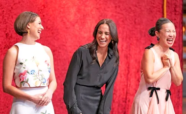 Meghan Markle standing beside MasterChef Australia judges Sofia Levin and Poh Ling Yeow laughing together.