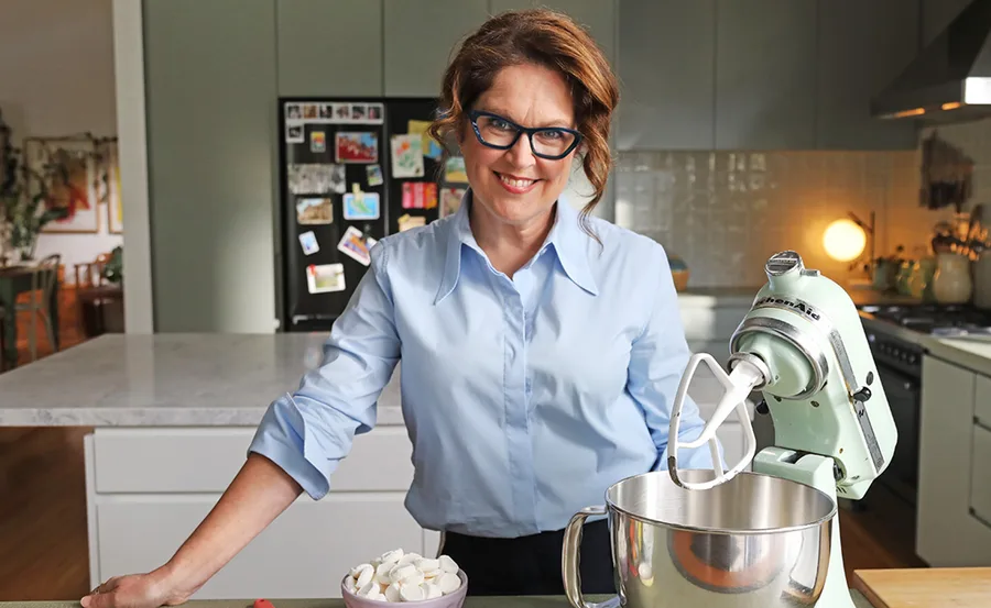 Annabel leans on a kitchen bench next to a mixer