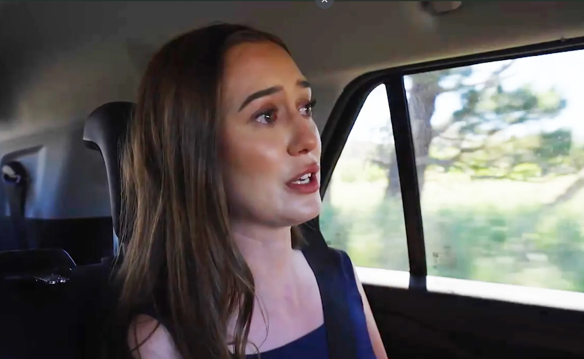 Yvonne, looking emotional, sits in the back of a car