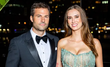 Jarrad, dressed in a black-tie outfit, stands next to Yvonne, wearing a shiny evening gown