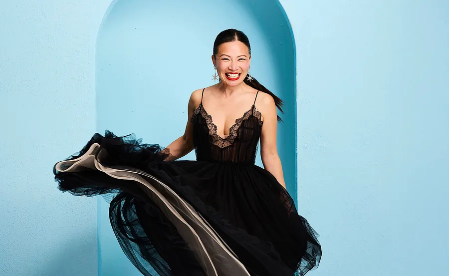 Poh Ling Yeow in a stunning black dress in front of a blue arched backdrop.