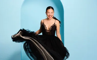 Poh Ling Yeow in a stunning black dress in front of a blue arched backdrop.