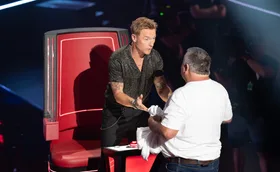 Ronan, standing up in front of his red chair, talks to Rodney