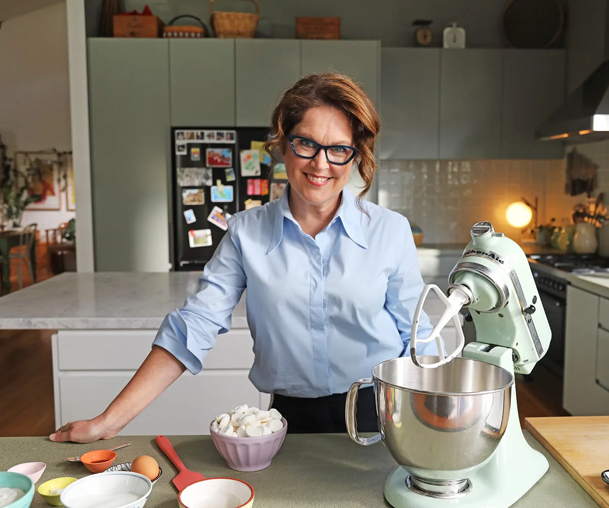 Annabel Crabb leans on a kitchen bench next to a mixer