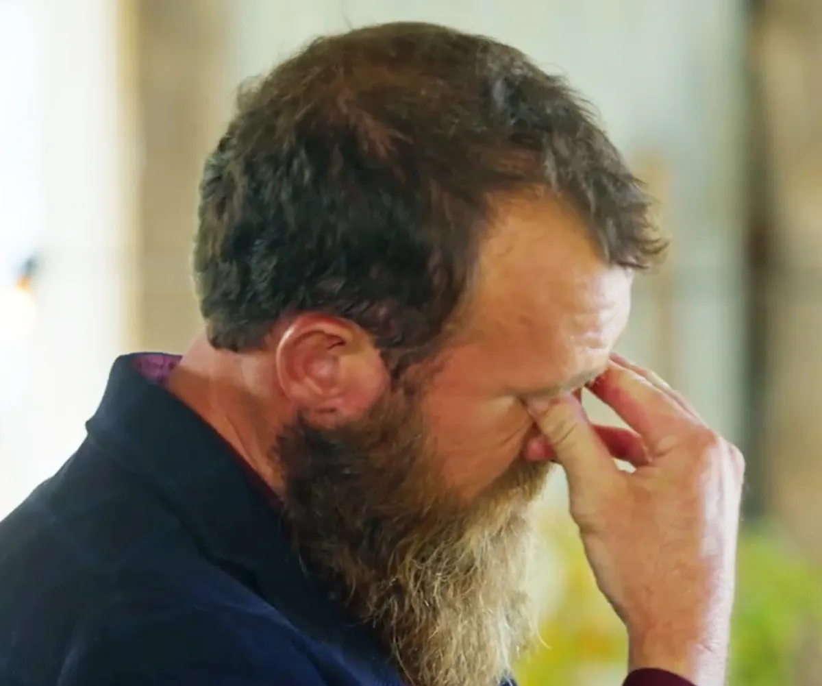 Jason covers his eyes with his fingers, looking upset