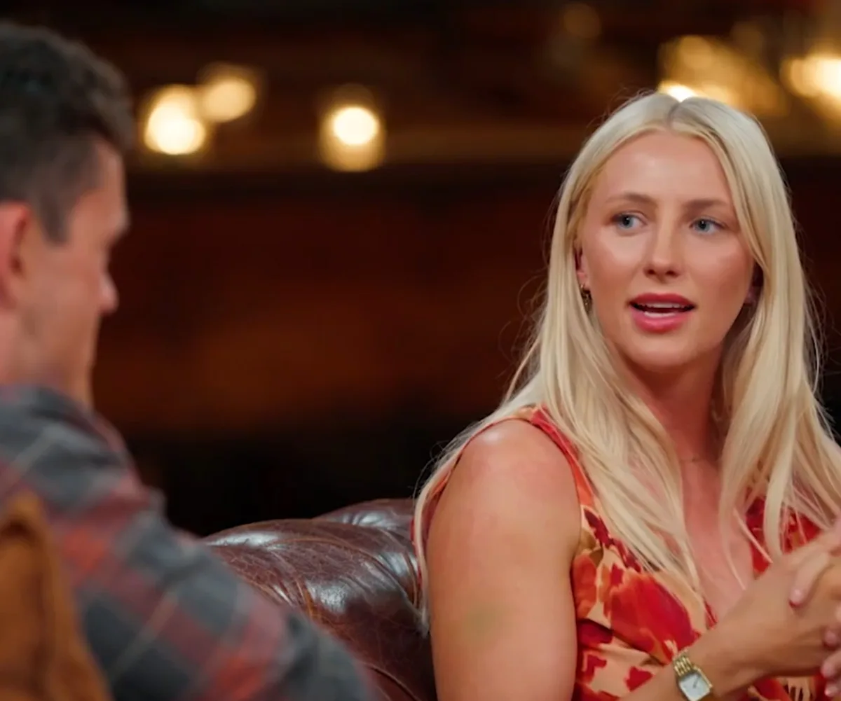 Eddy looks at Alex as they sit on the couch at the reunion