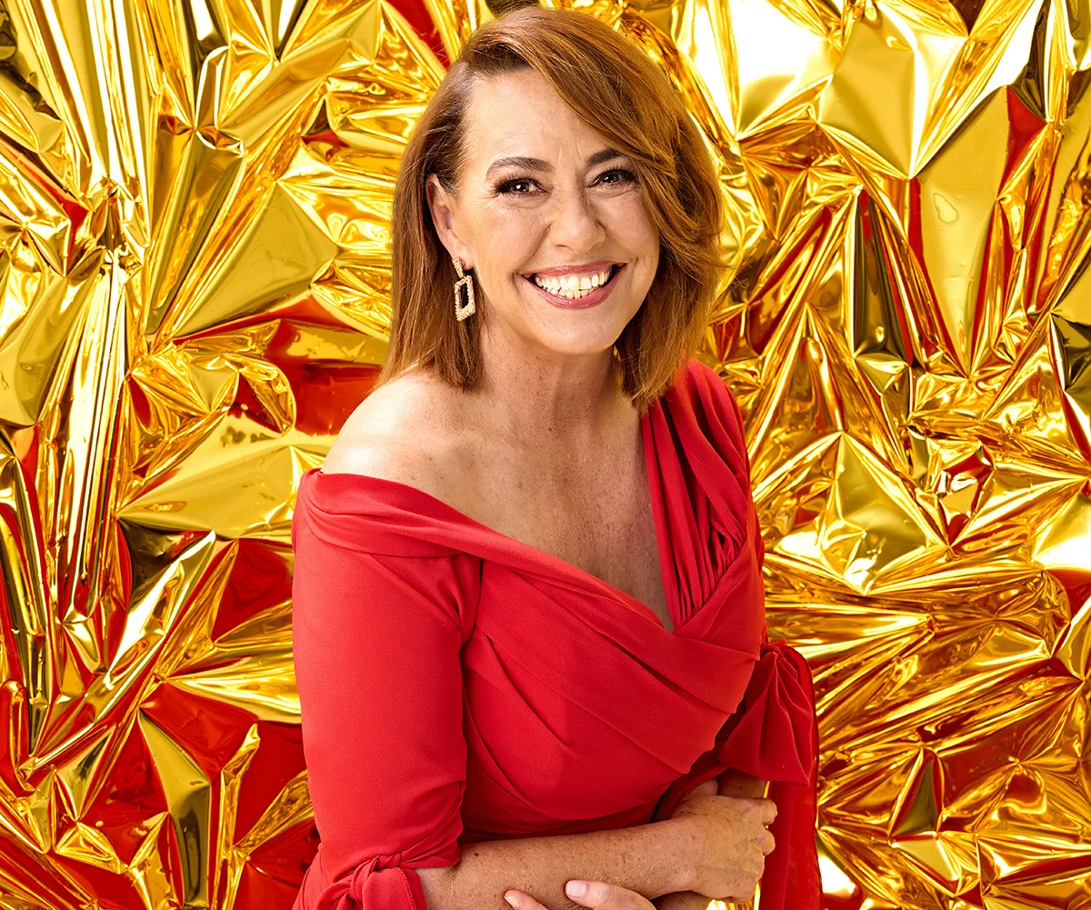 Lisa, in a red dress, stands in front of a gold background