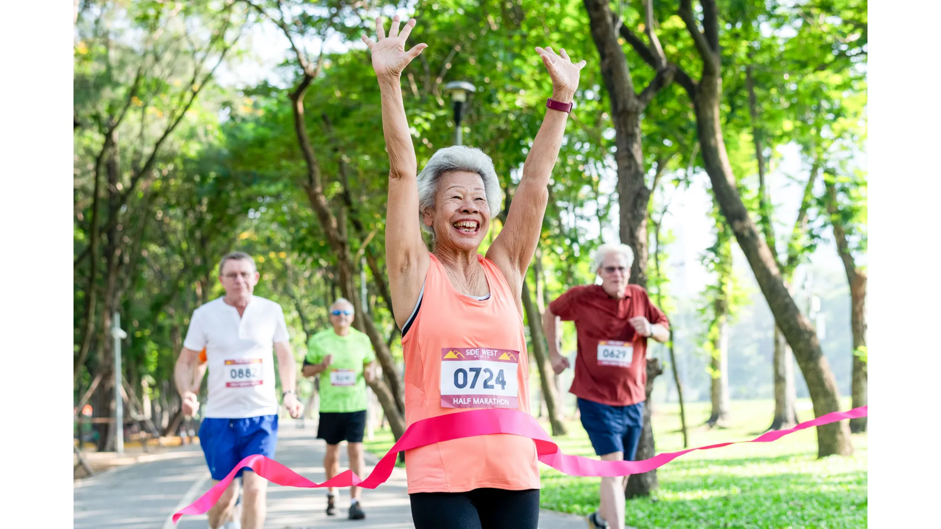 An older woman excitedly crosses the finish line at a half marathon. 