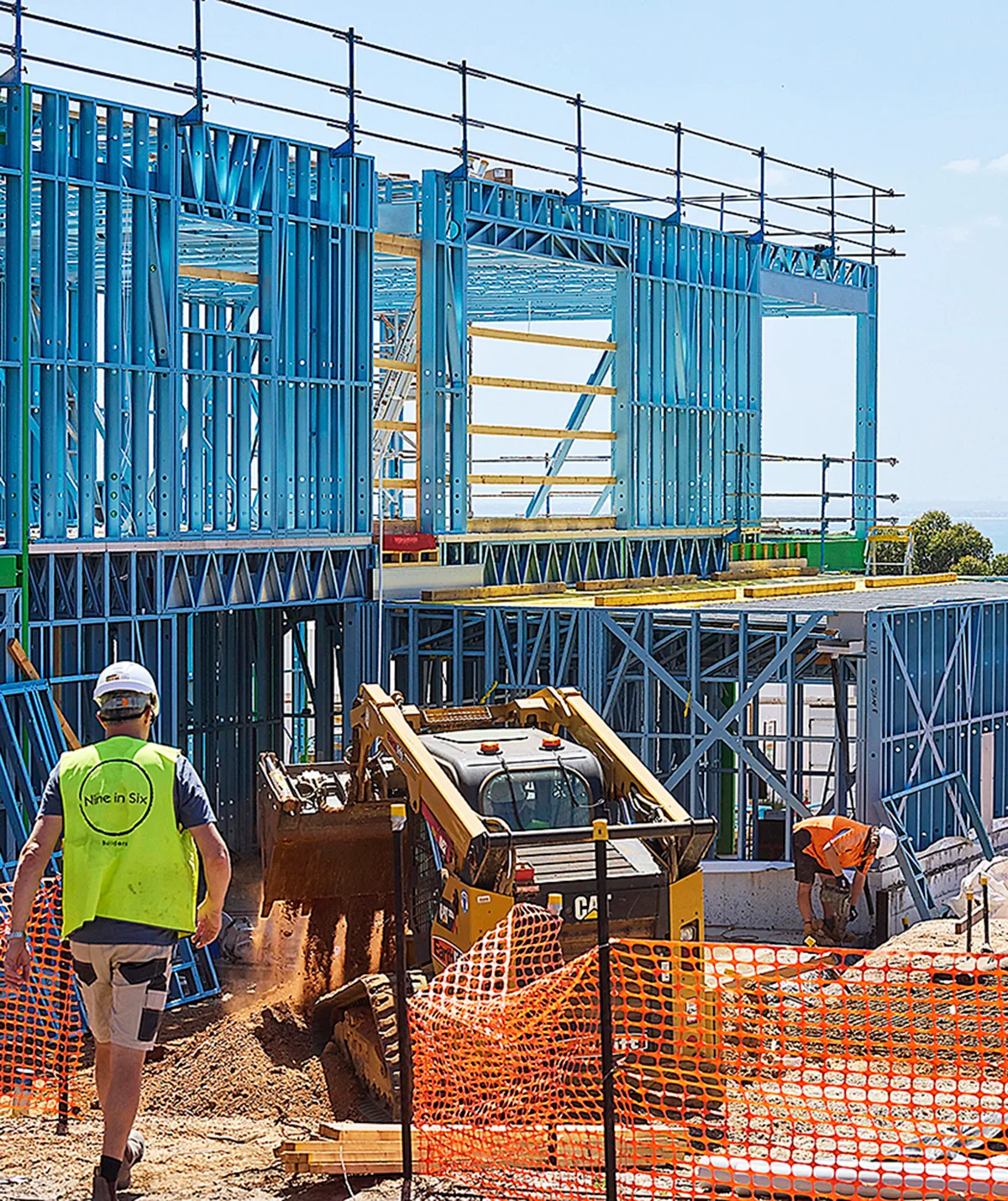 Tradie on site of The Block with a house structure behind him.