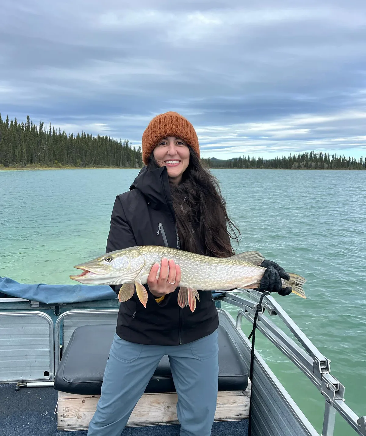 Alyce from Alone Australia season four on the back of the boat holding a fish.