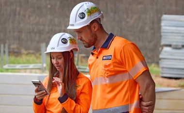 Lisa and Roscoe looking at a phone in hi-vis on set of The Block.