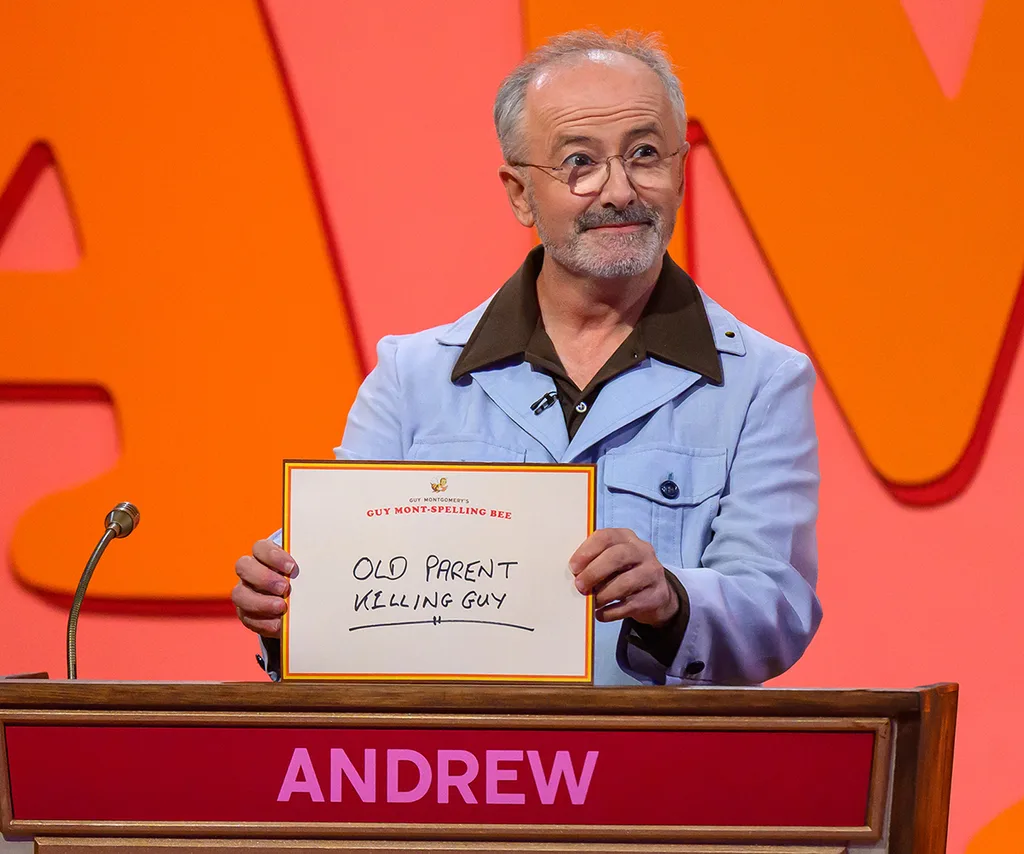 Andrew holds up an answer on the set of Guy Montgomery's Guy Mont-Spelling Bee