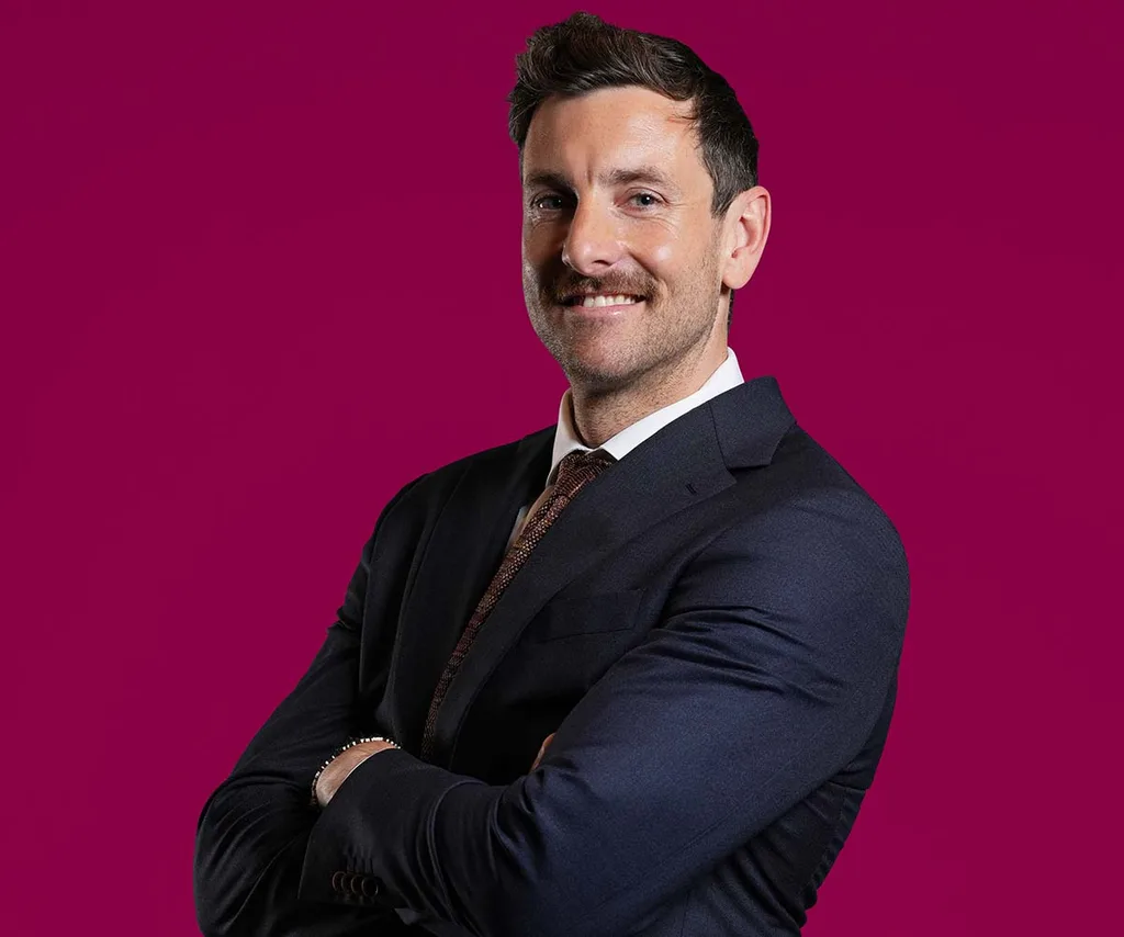 Henry in a suit in front of a dark red background