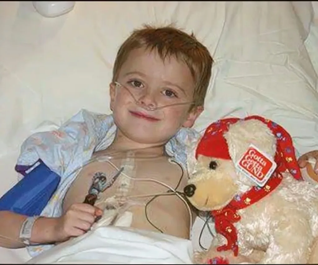 A three-year-old Findlay lies in a hospital bed with a soft toy next to him