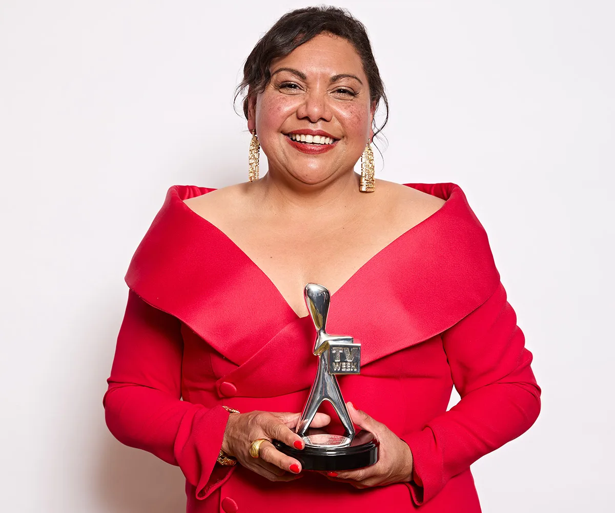 Deb, wearing a red dress, holds a Logie