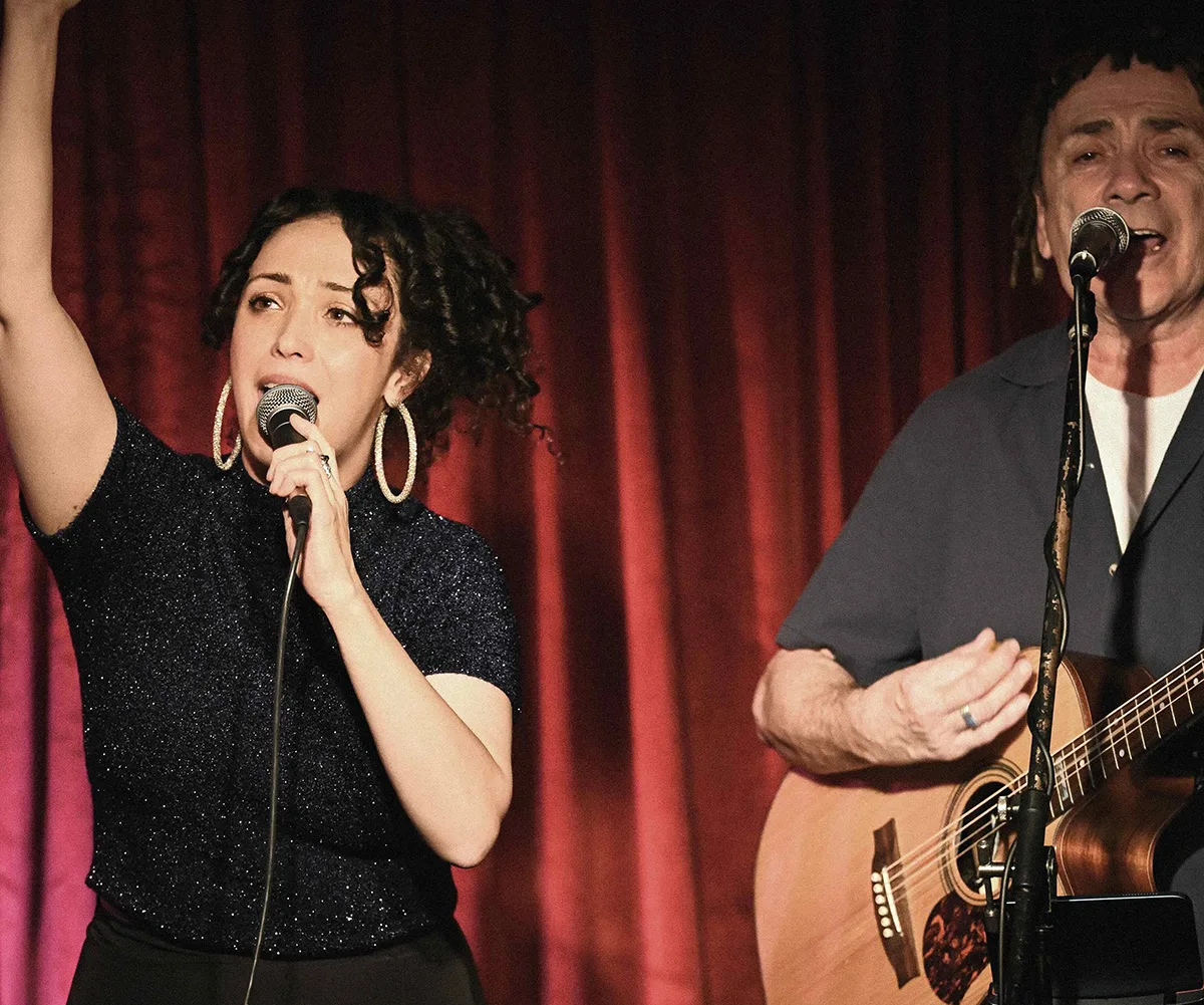 Taylor singing on stage, next to her dad Mark holding a guitar