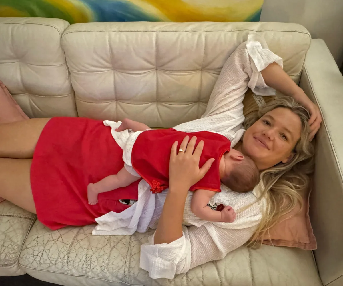 Leah Stewart lies on lounge holding her baby daughter