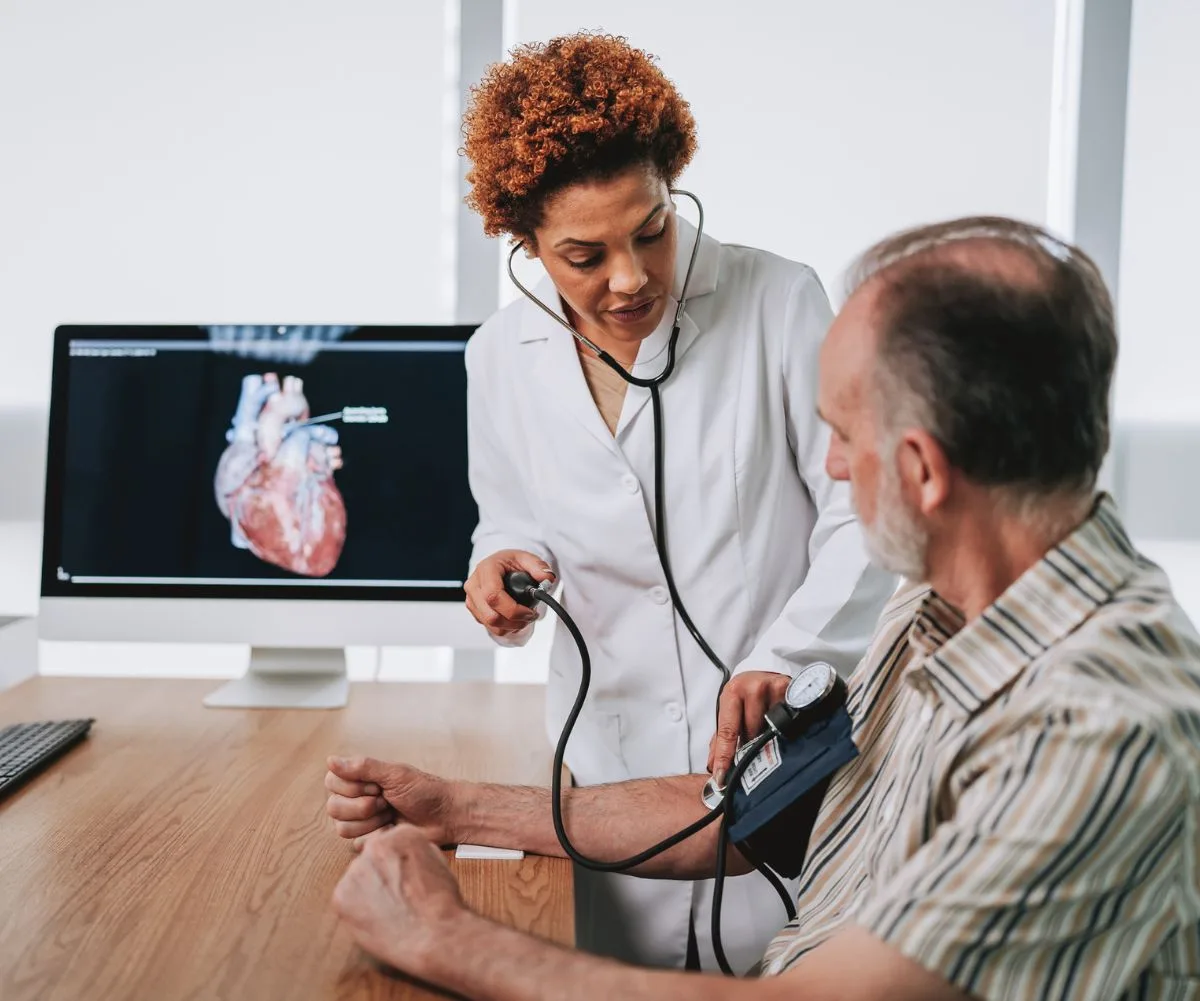 Female doctor checking older man's heart health