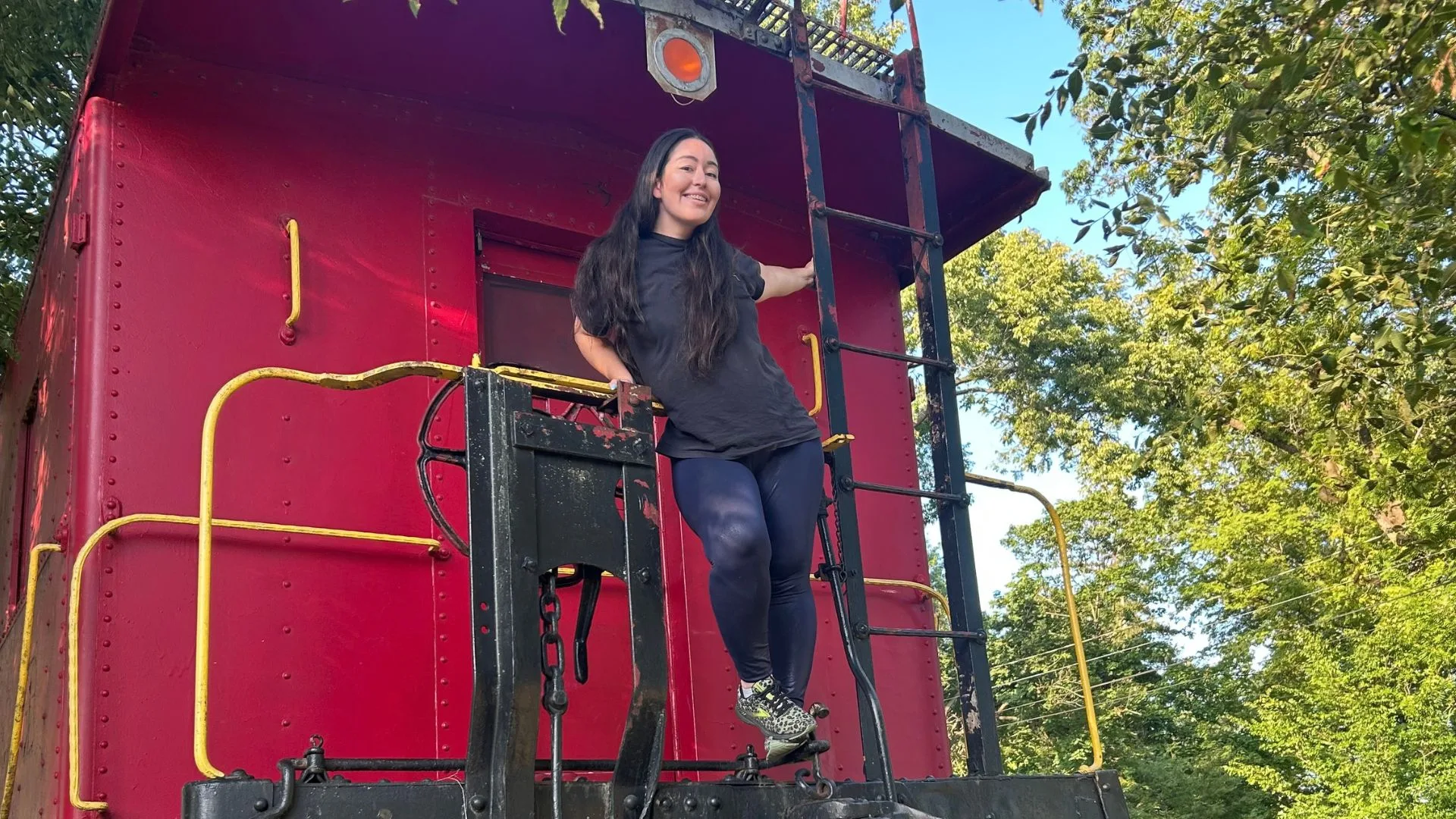 Kathryn Andrea is standing on the back of a train.