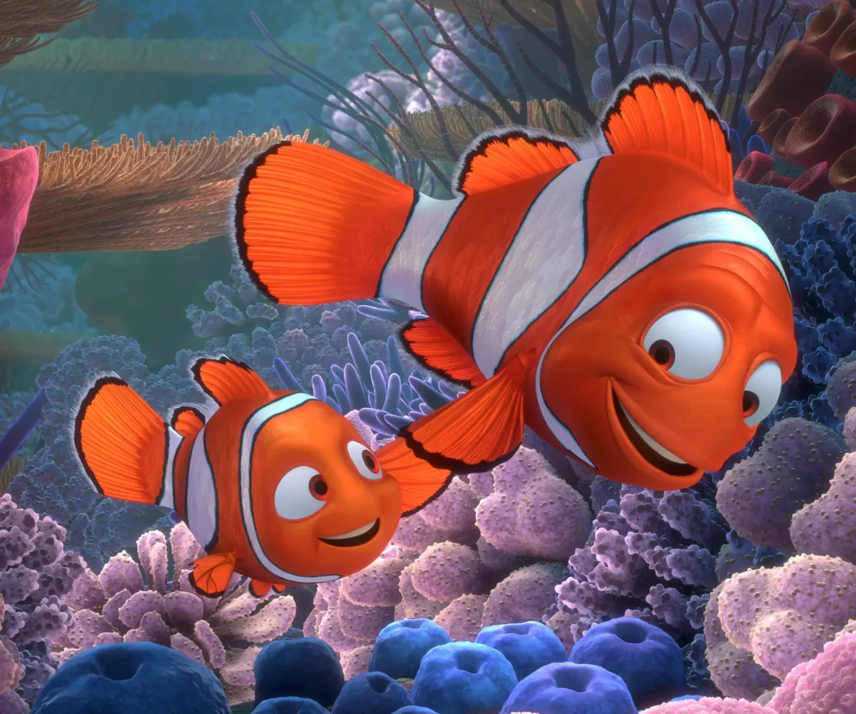 Nemo the clown fish and his dad smile at each other as they swim through the reef in the movie Finding Nemo