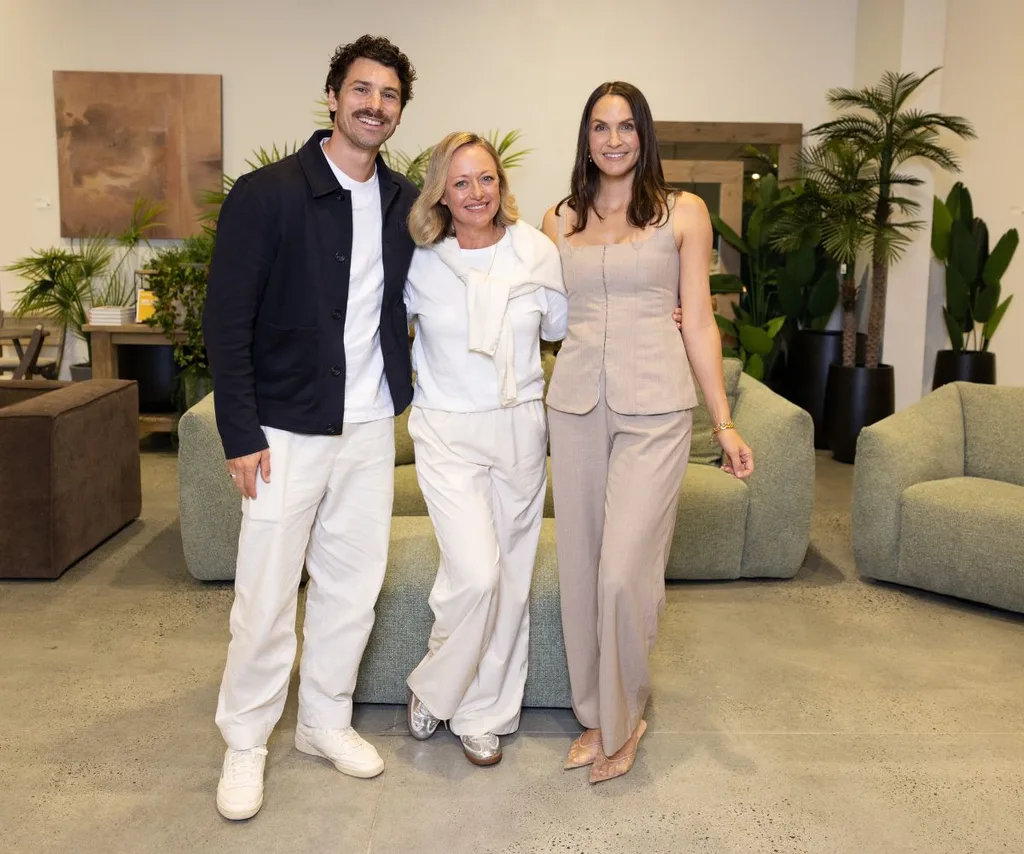 Matty J, Shelley Craft and Laura Byrne pose in front of green lounges while smiling.