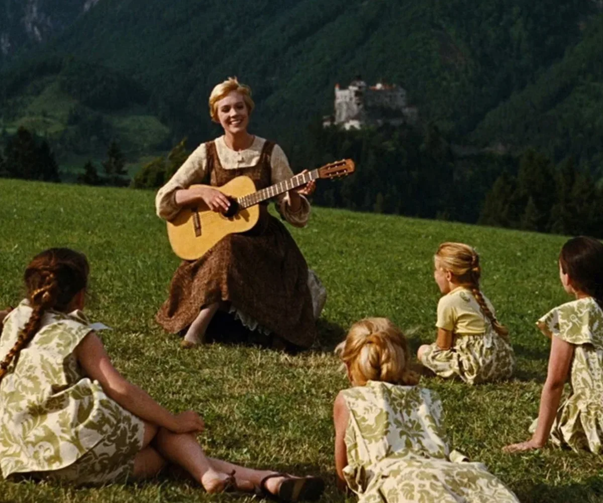Julie Andrews playing Maria sings to the children on the grass in The Sound Of Music