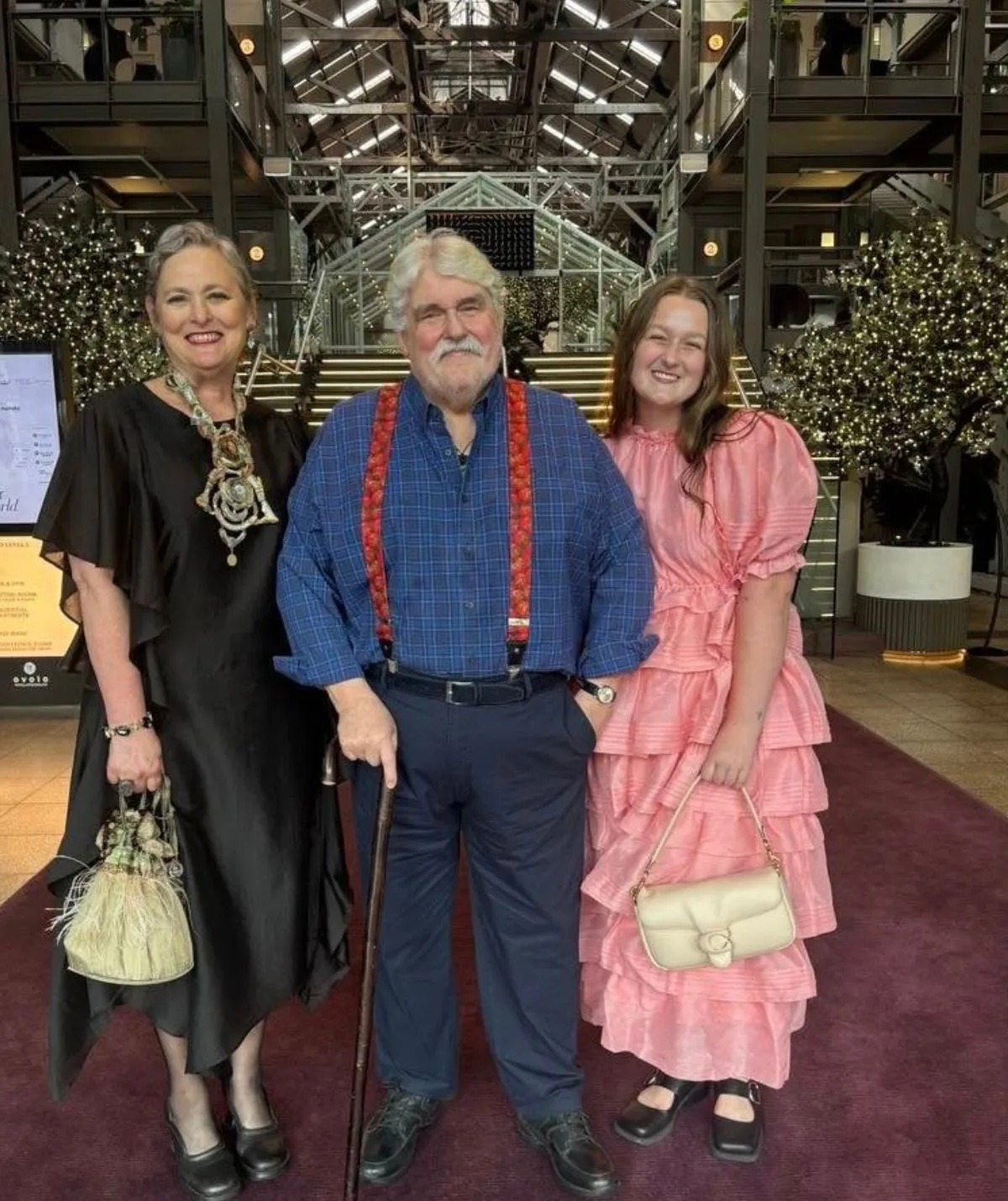 Huey and his wife and daughter smiling on a red carpet. 