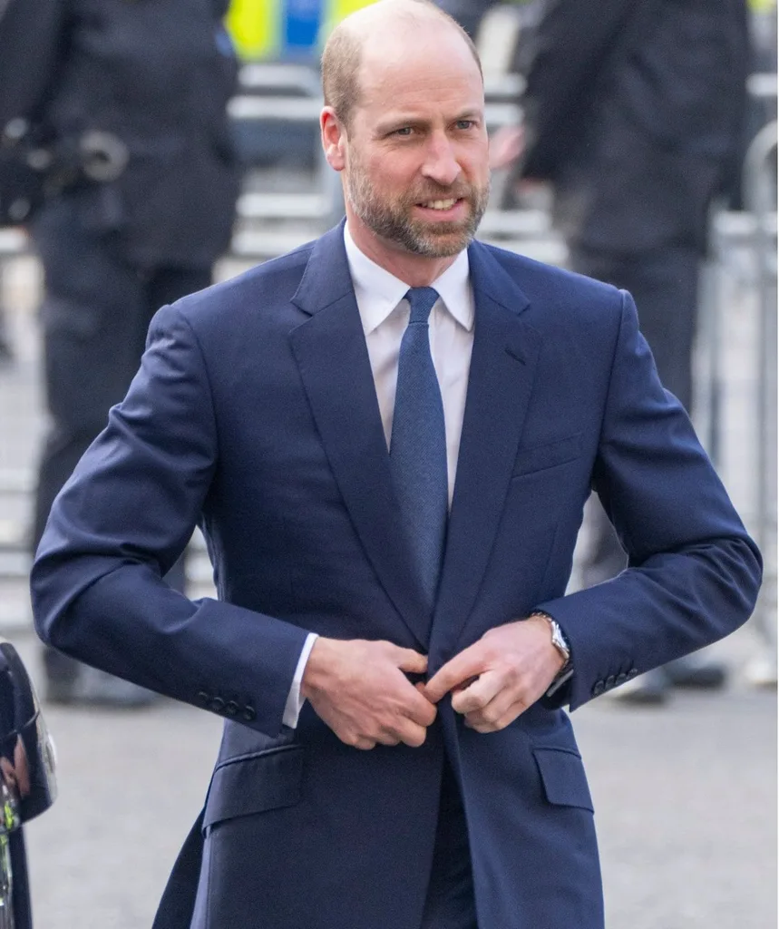 William in a blue suit looking tense.
