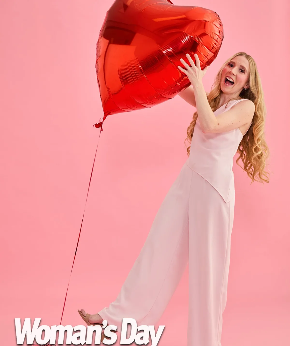 Nikki Webster smiling holding giant red inflatable balloon