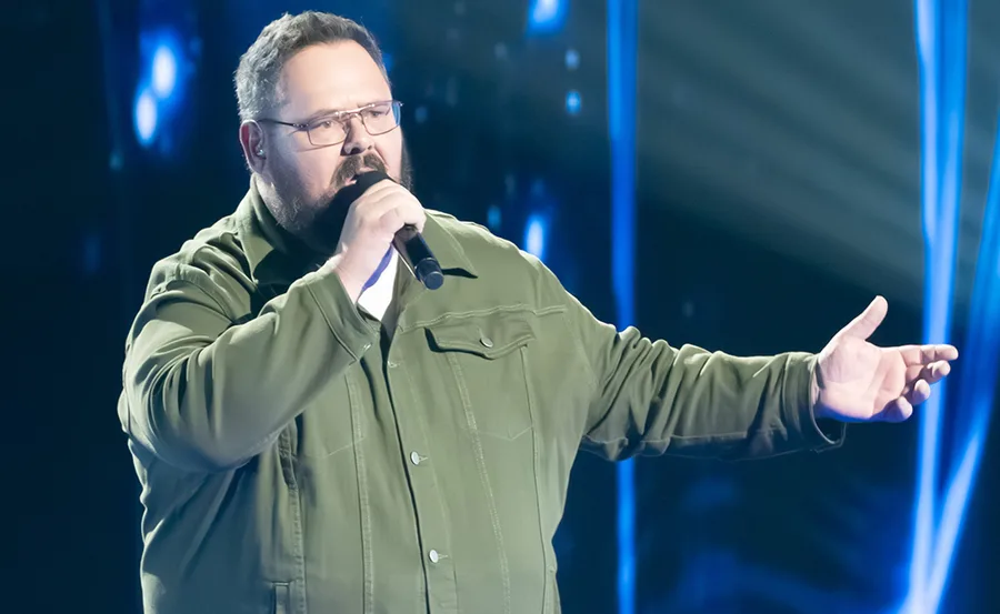 Dicko, in an olive shirt, singing on the set of The Voice