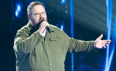 Dicko, in an olive shirt, singing on the set of The Voice