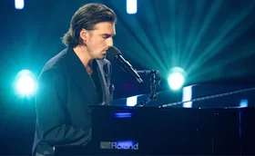 Tommy plays the piano in front of blue lights