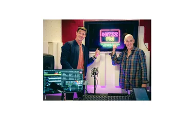 Ed Kavalee and Rob Sitch point to a sign behind them