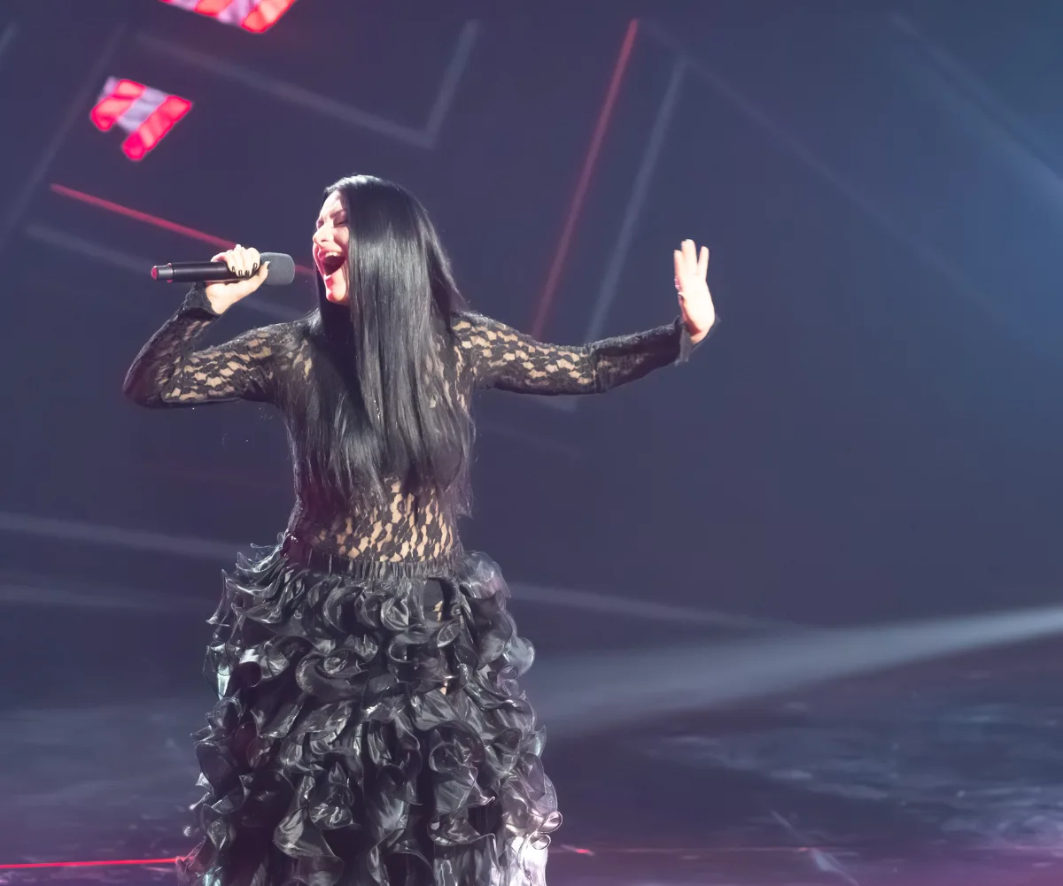 Victoria, in a long black dress, sings on the set of The Voice
