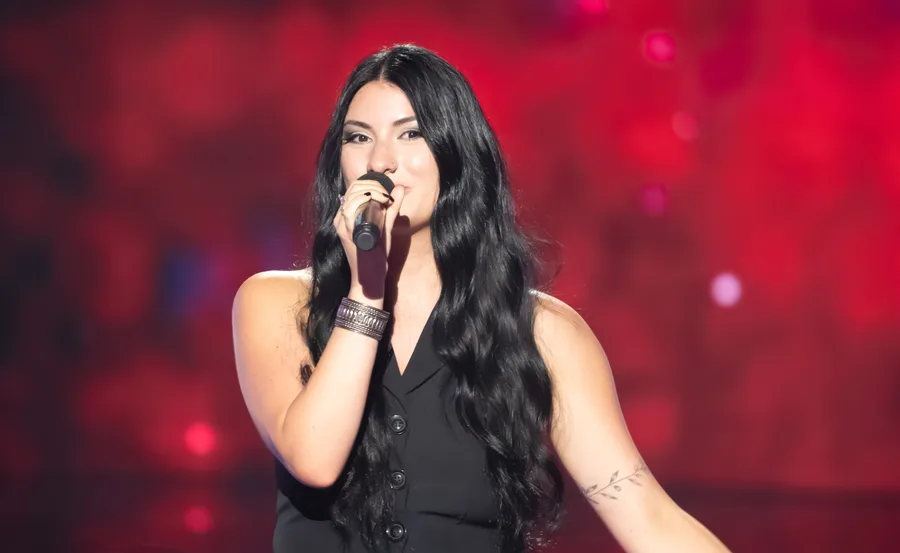 Victoria sings on The Voice in front of a red background