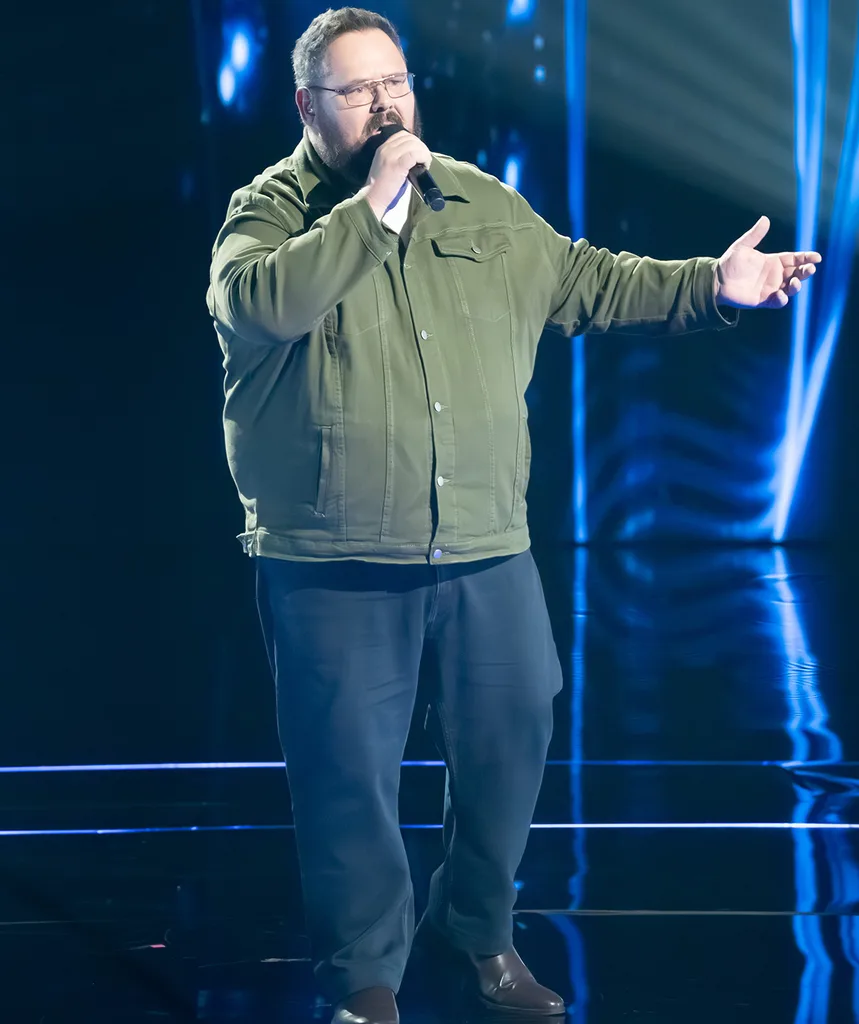 Dicko, in an olive shirt, singing on the set of The Voice
