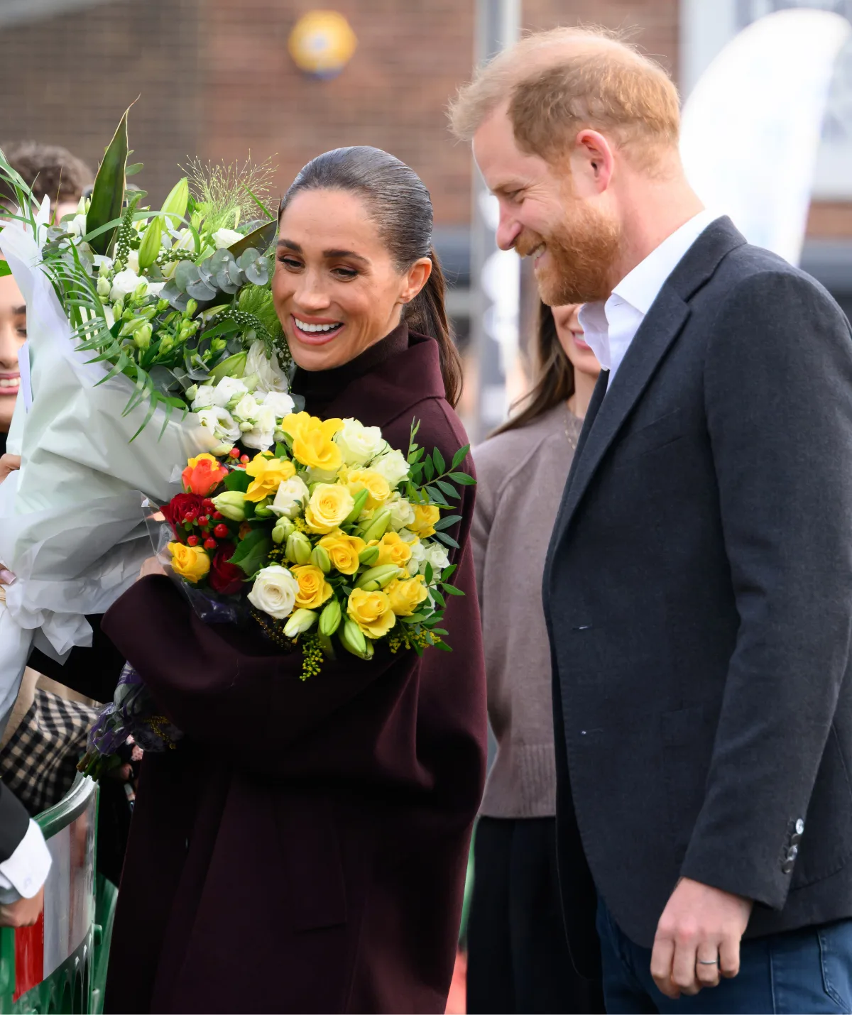 Meghan Markle clutching bouqets of flowers as Prince Harry looks on 