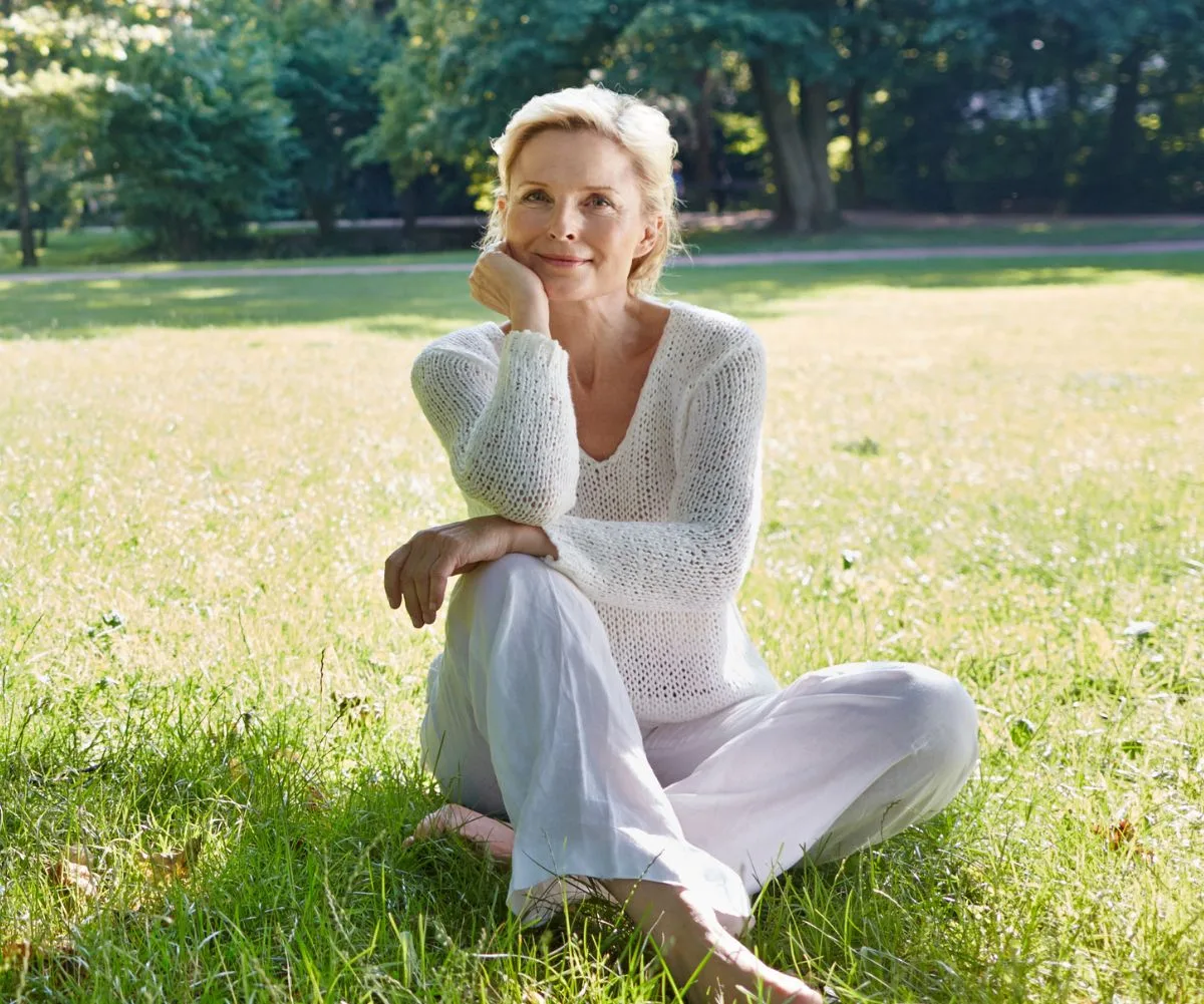 Older woman sitting in grass field